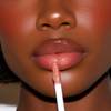 Close-up of a model's lips applying a glossy, shimmery pink lip gloss with a white applicator wand.