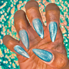 Model displaying hands with ocean blue neon diamond jelly cat eye gel polish featuring a luminous reflective finish with a shimmering 3D effect