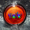 Shimmering molten tangerine golden chrome highlighter makeup compact with 'mocha made cosmetics' branding on a glittery background