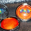 Shimmering molten tangerine golden chrome highlighter makeup compact with 'mocha made cosmetics' branding on a glittery background